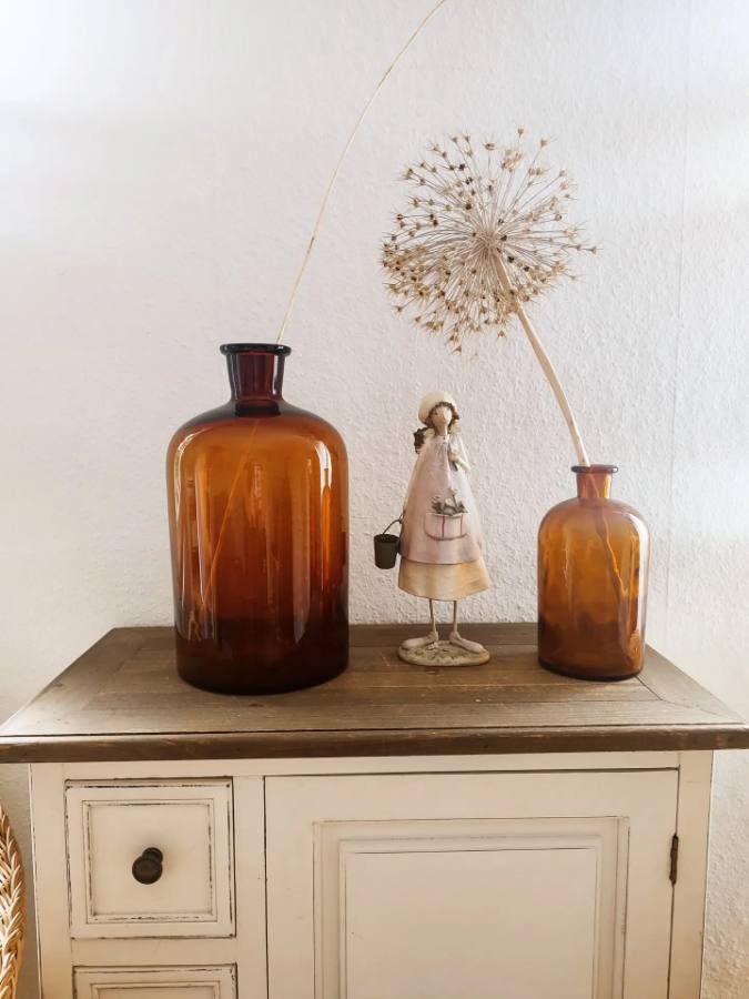 Braune Apothekerflaschen mit Pusteblumen als Dekoration